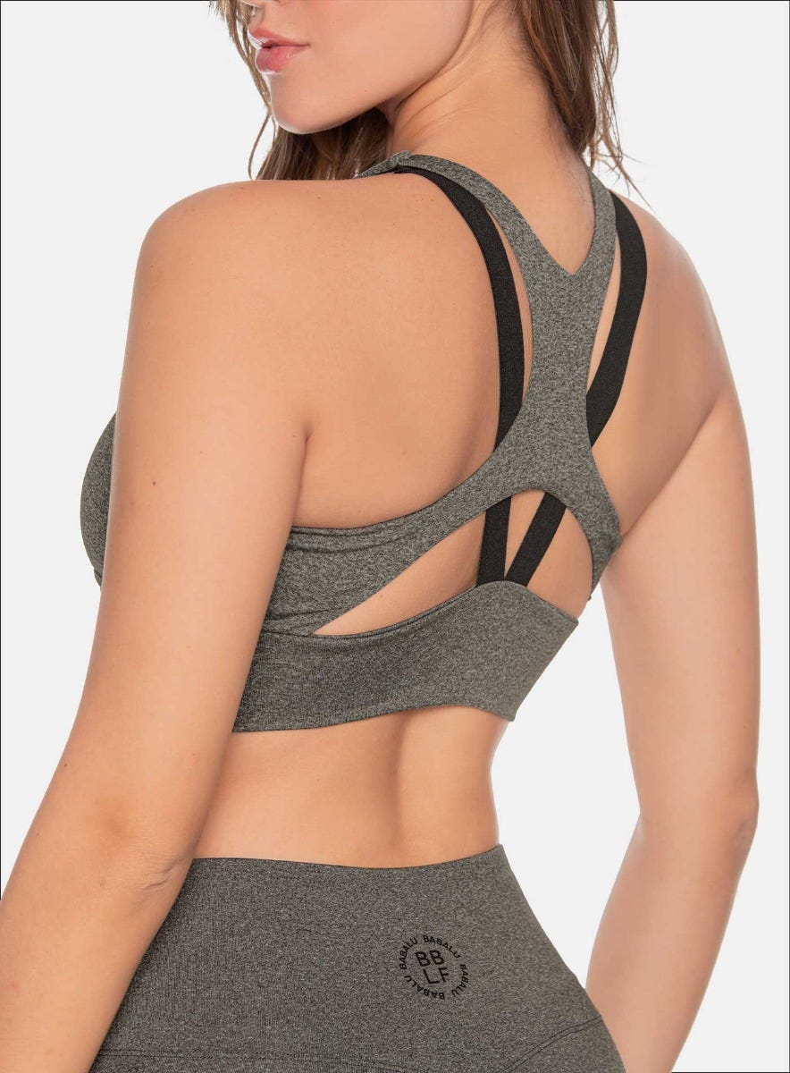 TOP DEPORTIVO CON SESGOS AEREOS DECORATIVOS, FORRO INTERNO, ELÁSTICO EXPUESTO EN LA ESPALDA Y APLQUE DECORATIVO EN EL FRENTE.